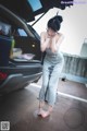 A woman standing next to a car with her head in her hands.