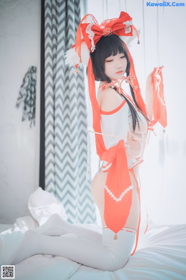 A woman in a red and white outfit sitting on a bed.