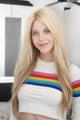 A woman with long blonde hair wearing a rainbow sweater.