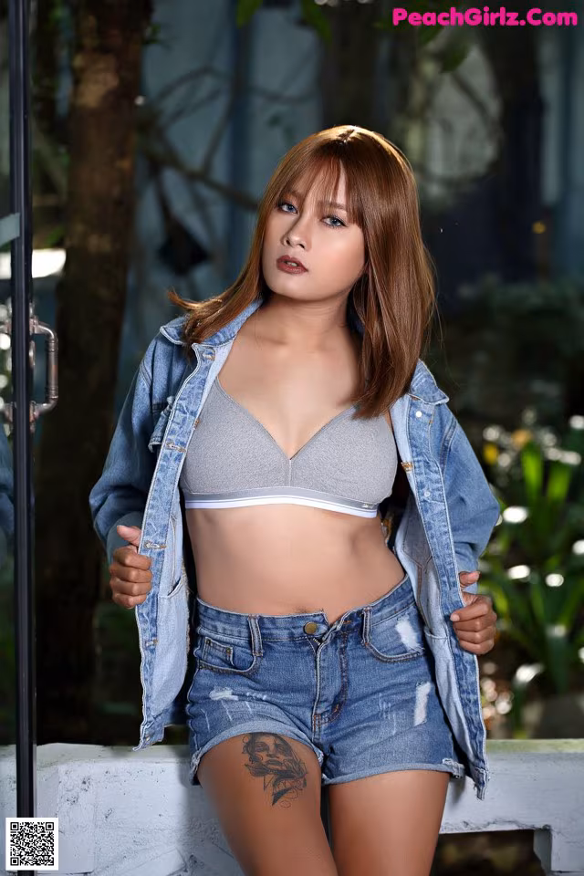 A woman in a gray bra top and denim shorts posing for a picture.