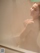 A naked woman taking a shower in a bathtub.