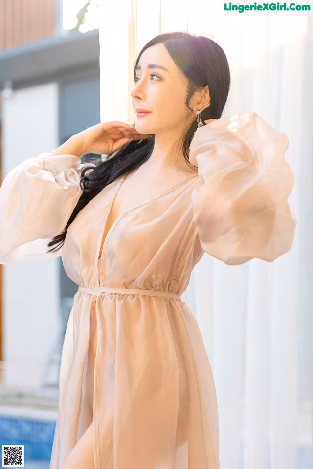 a woman in a pink dress standing by a window