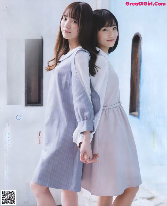 A couple of women standing next to each other in front of a building.