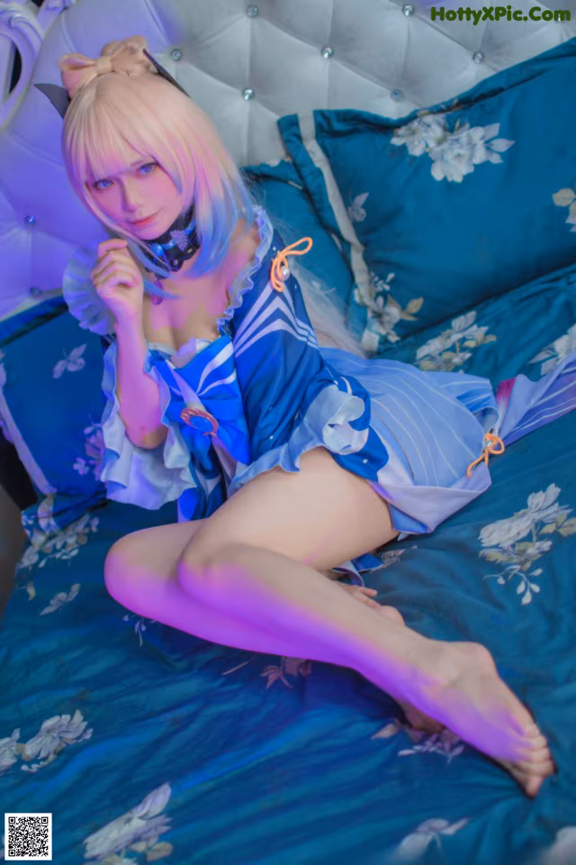 A woman in a blue and white outfit sitting on a bed.