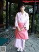 A woman in a pink kimono poses for a picture.