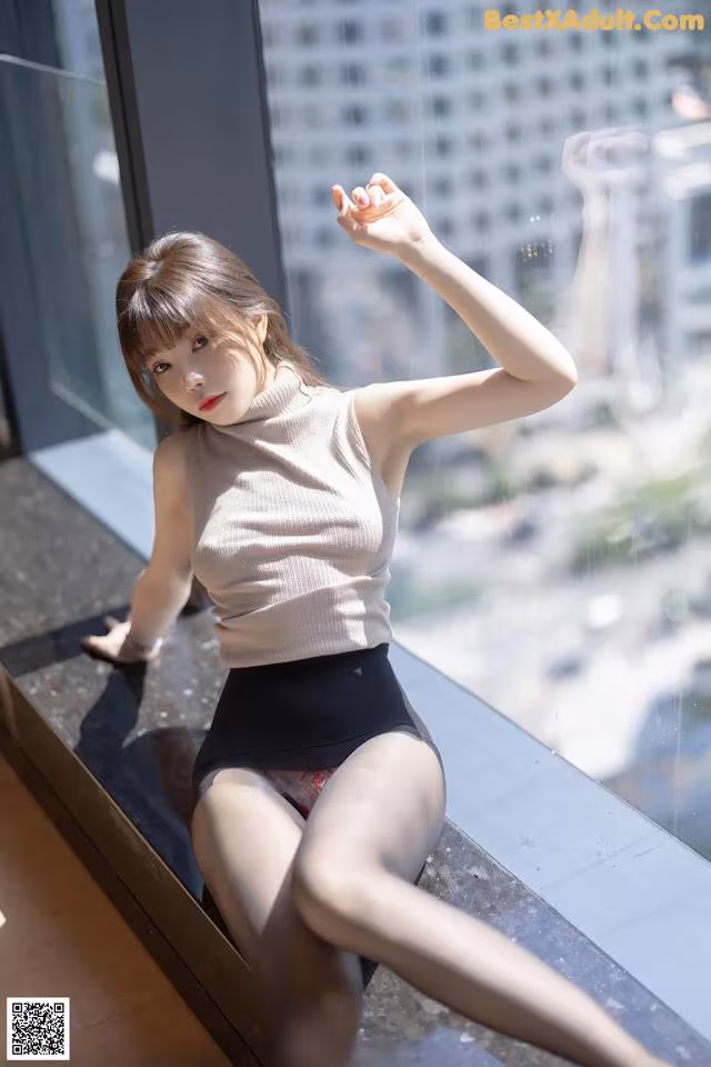 A woman sitting on a window sill in a black skirt.