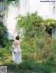 A woman in a white dress walking through a garden.