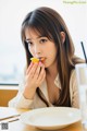 A woman sitting at a table eating a piece of fruit.