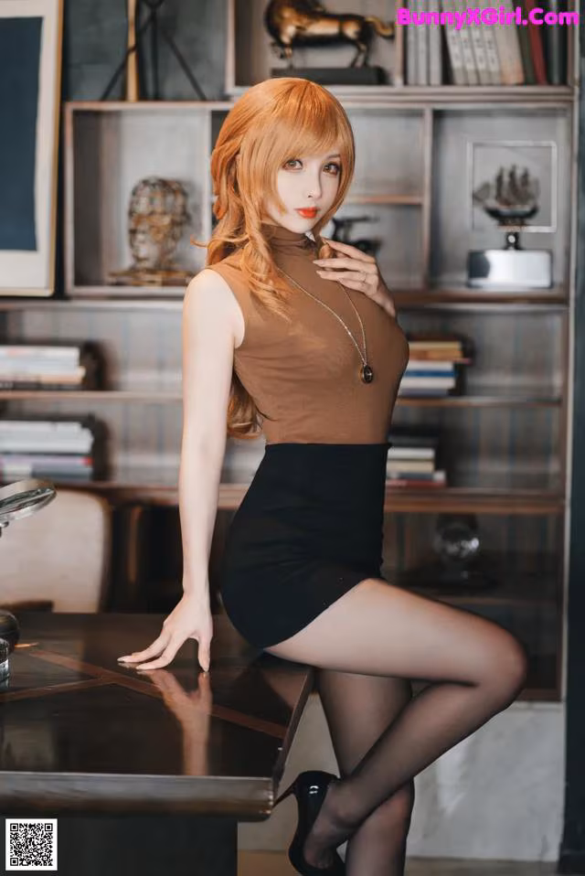 A woman in a brown top and black skirt posing for a picture.