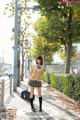 A woman in a school uniform is walking down the street.