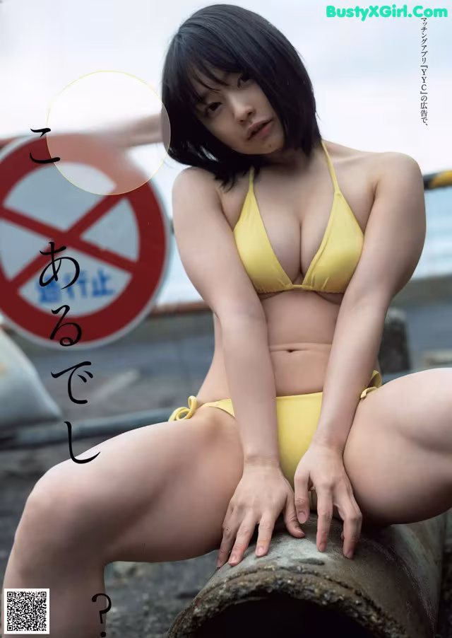 A woman in a yellow bikini sitting on a pipe.