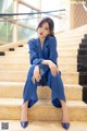 A woman in a blue suit sitting on some stairs.