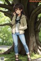 A girl standing next to a tree talking on a cell phone.