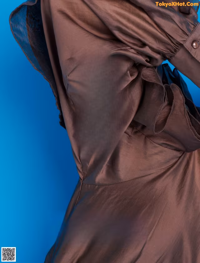 A woman in a brown dress with a blue background.