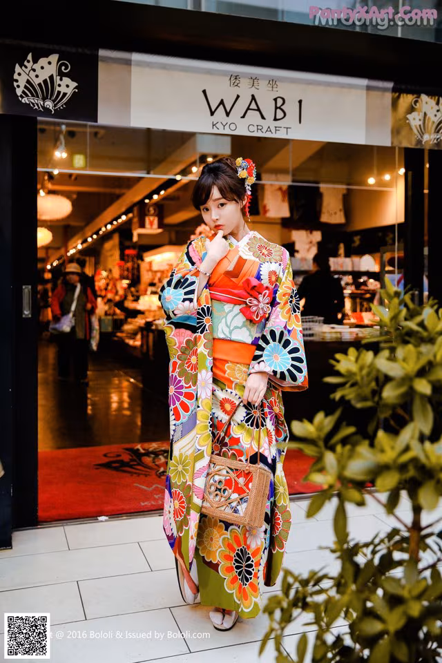 A woman in a colorful kimono standing in front of a store.
