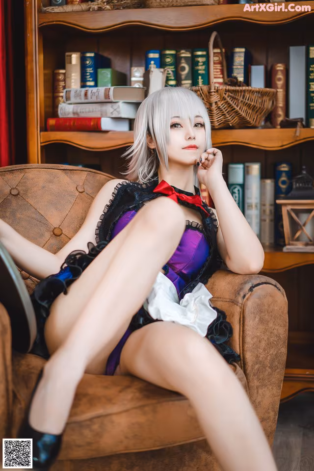 A woman sitting on a couch in front of a book shelf.