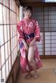 A woman in a red and white kimono posing for the camera.