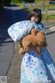 A little girl holding a teddy bear and a pillow.