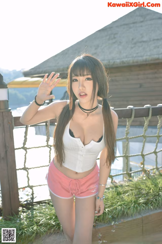 A woman in a white top and pink shorts posing for a picture.