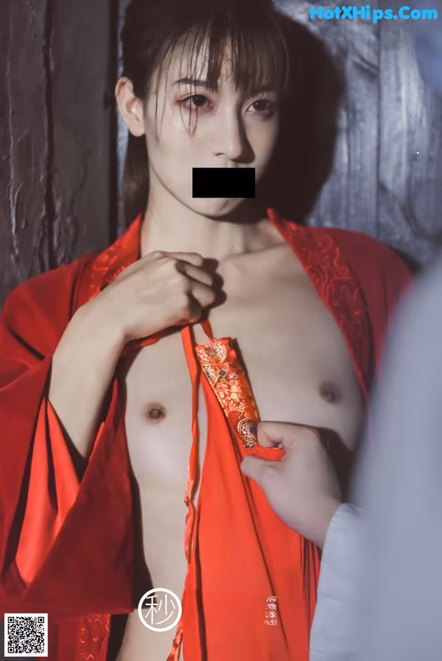 A man in a red kimono is holding a red scarf.