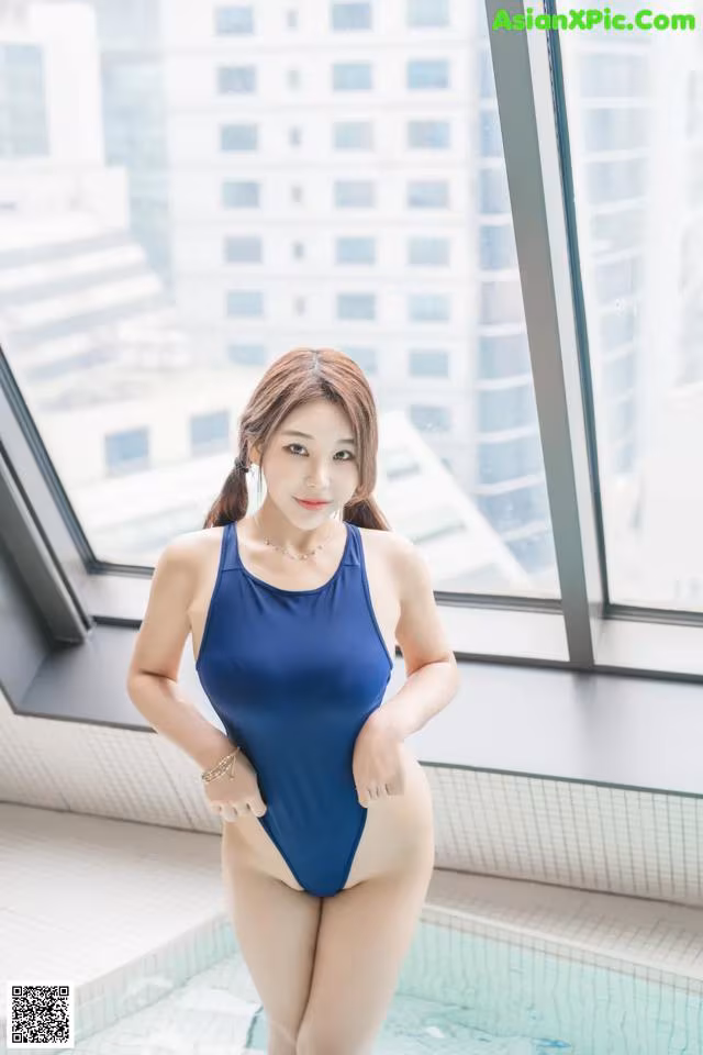 A woman in a blue swimsuit standing in a swimming pool.