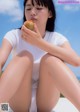 A woman sitting on a white bench eating an apple.