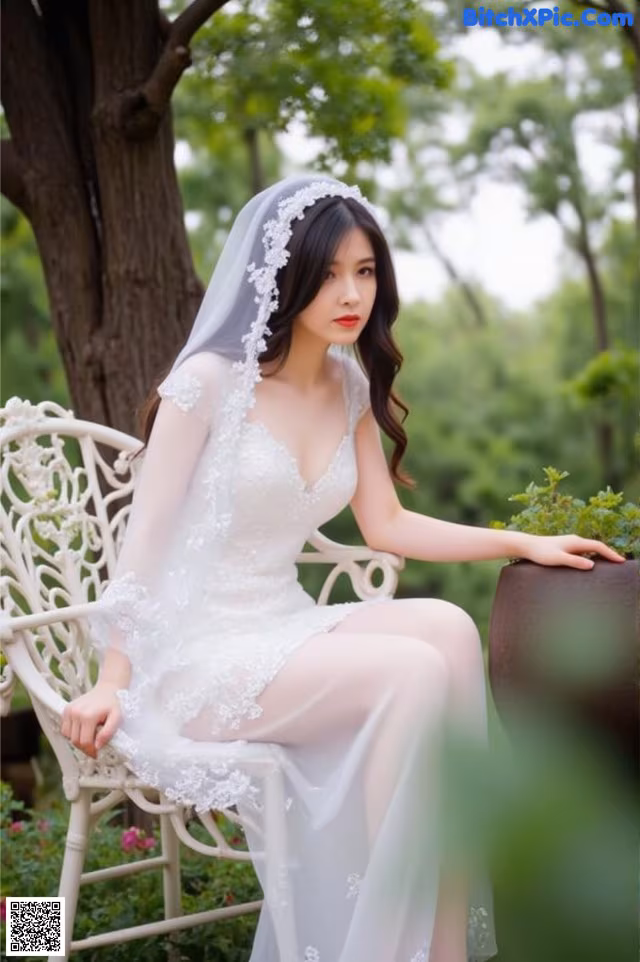 A woman in a wedding dress sitting on a white chair.