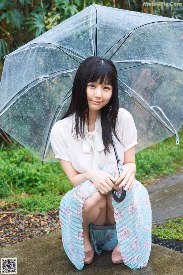 A woman sitting on a bench holding an umbrella.