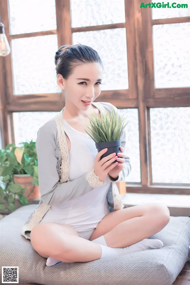 A woman sitting on a couch holding a potted plant.