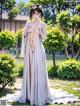 A woman in a white kimono standing in a garden.